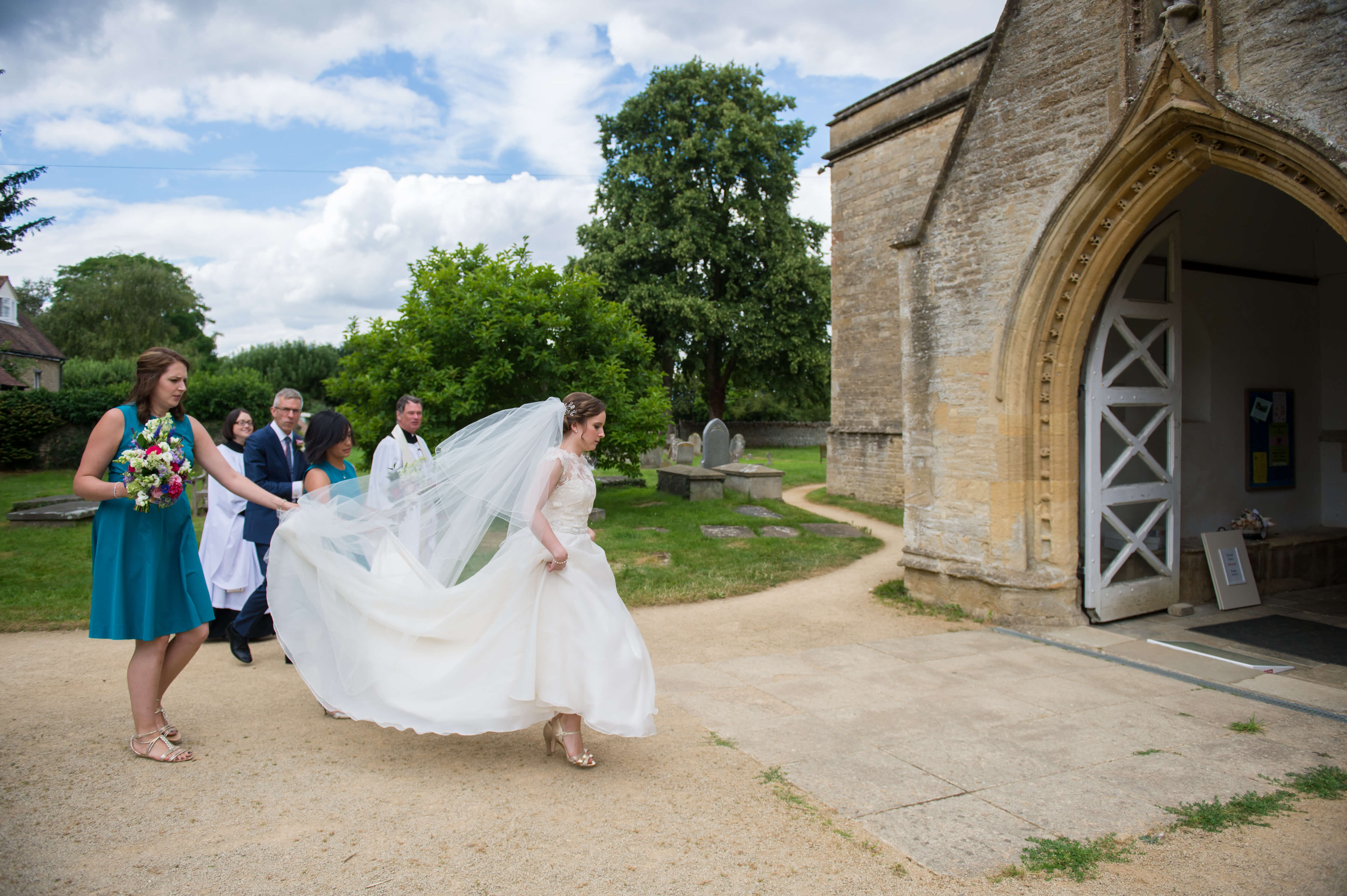 A bride walking into the church with her bridesmaids in Oxfordshire